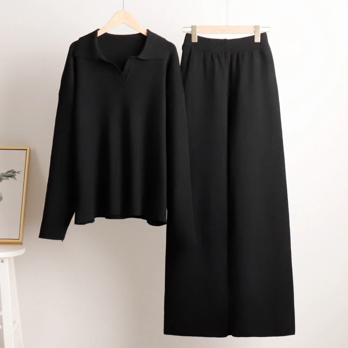 Black long-sleeve top and black skirt on hangers against a white background