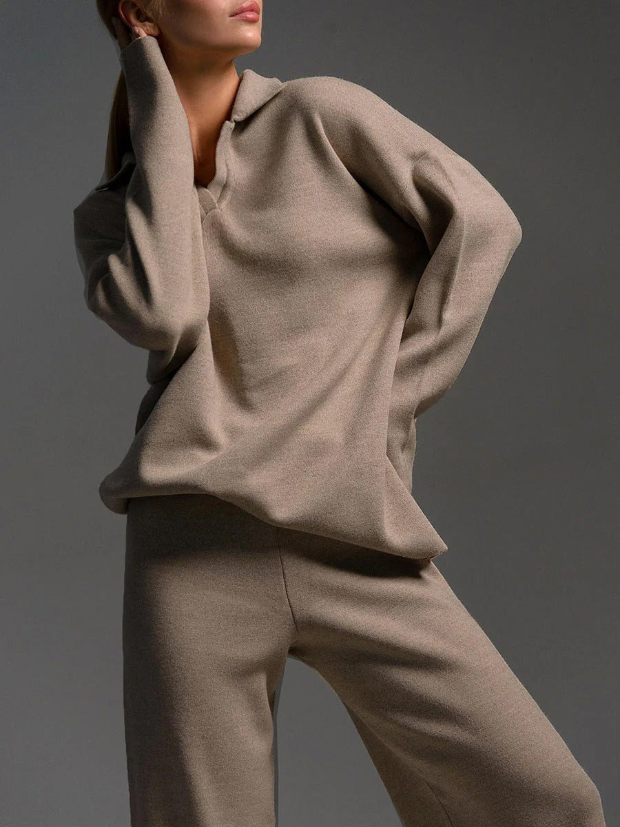 Person wearing a beige sweater and pants against a gray background