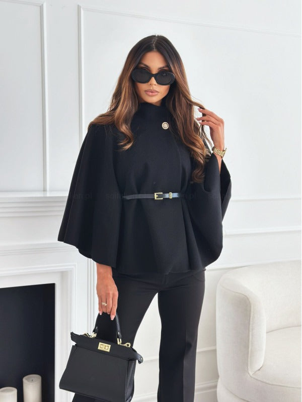 Woman in a black outfit with sunglasses holding a black handbag in a white room.