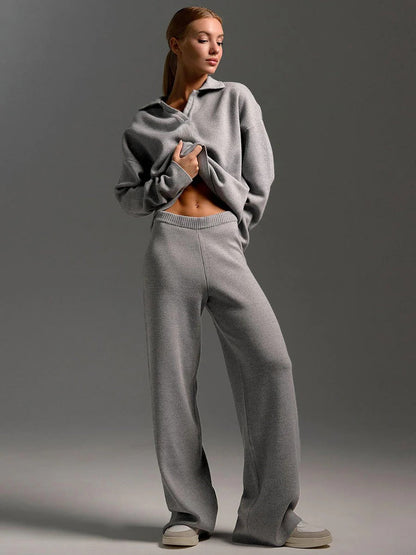 Person wearing a gray tracksuit against a plain background