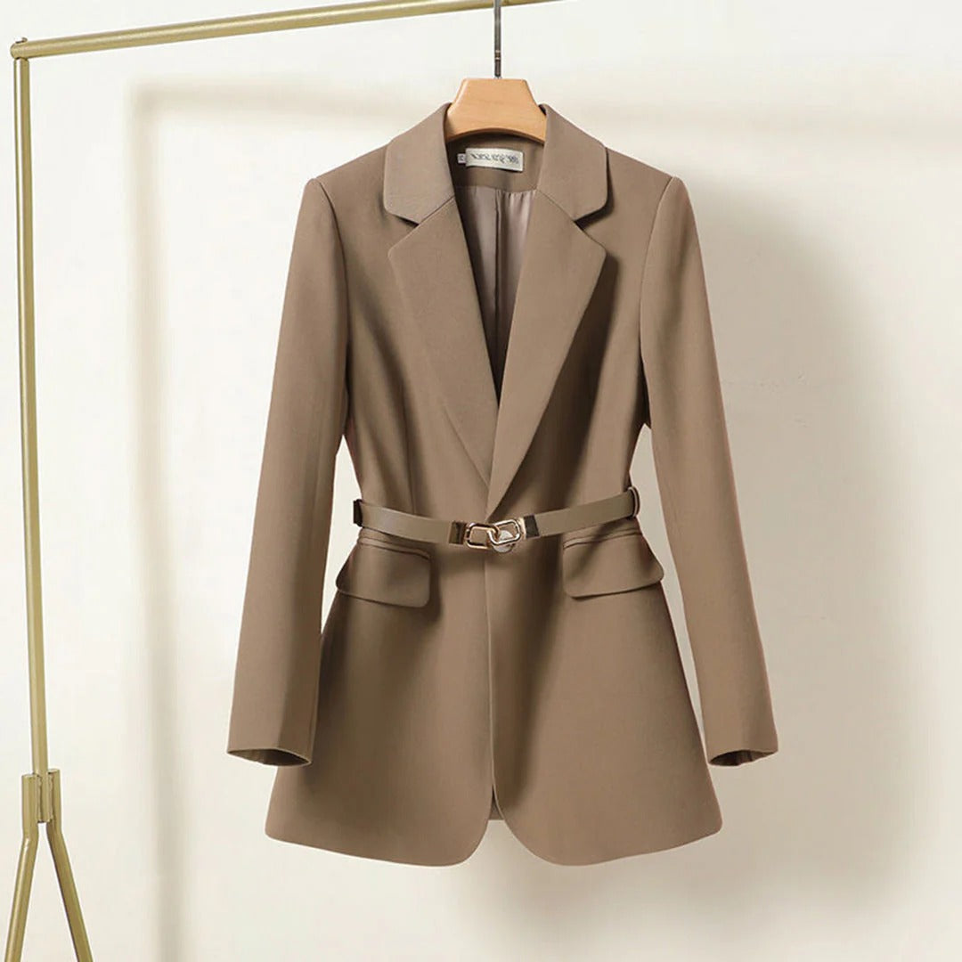 Brown blazer with a belt on a hanger against a beige background