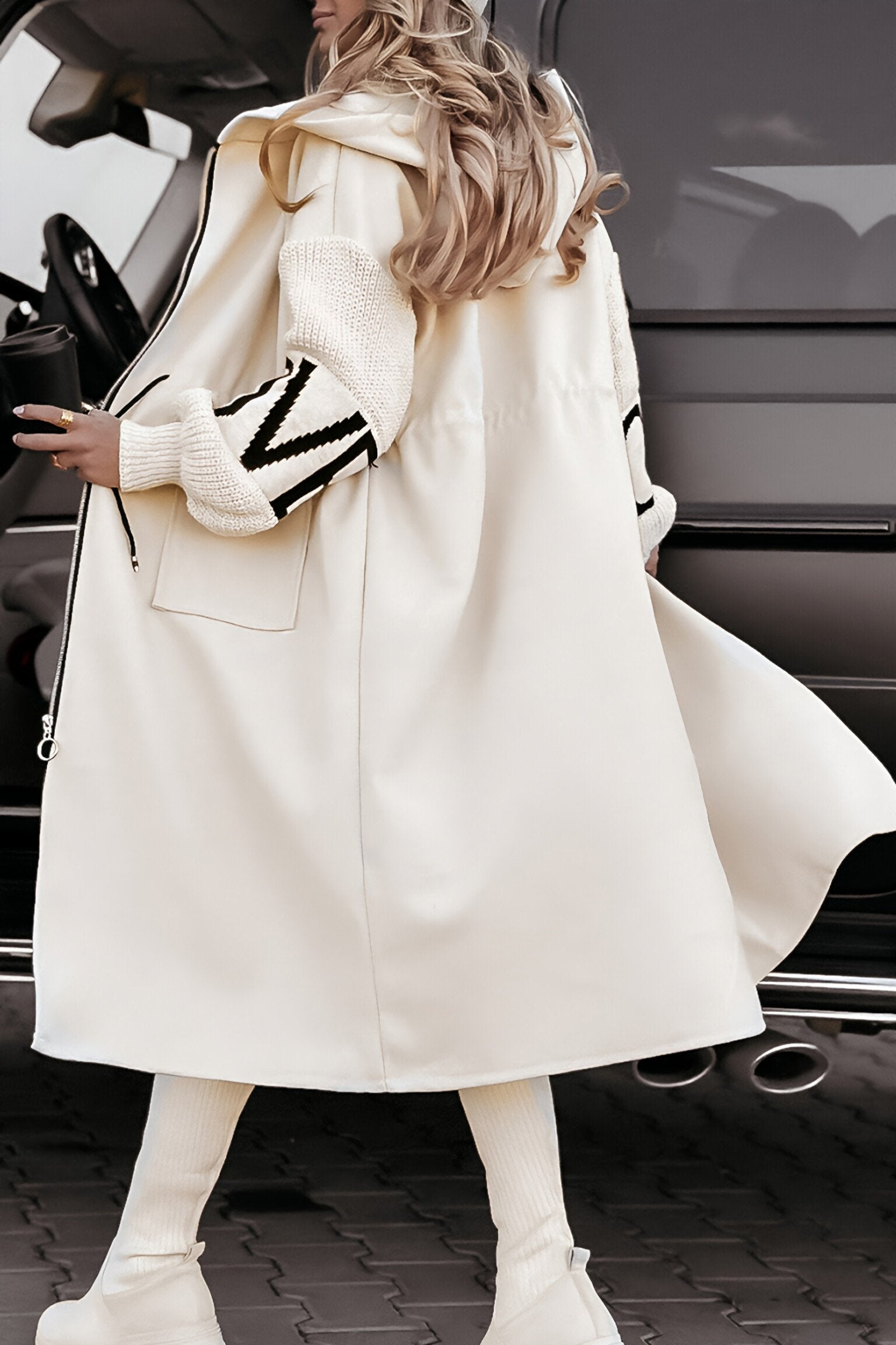 Person wearing a long white coat with a car in the background