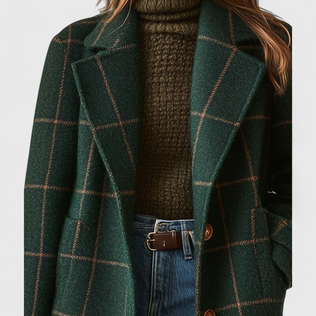 Green plaid coat over a brown sweater and blue jeans on a white background