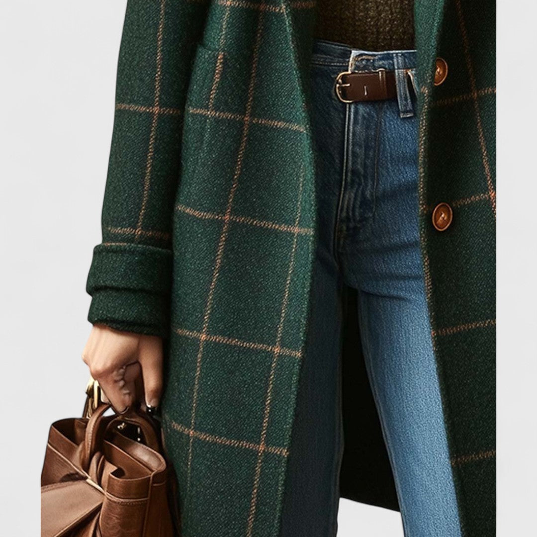 Person wearing a green plaid coat with blue jeans and holding a brown leather bag.