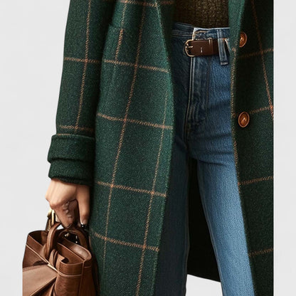 Person wearing a green plaid coat with blue jeans and holding a brown leather bag.