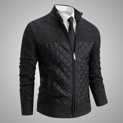 Black quilted jacket with a white shirt and tie on a gray background