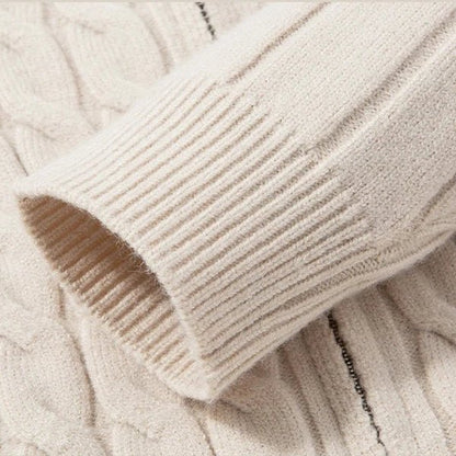 Close-up of a beige cable knit sweater with a soft texture.