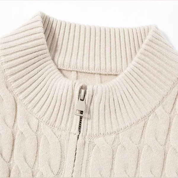 Close-up of a beige cable knit sweater with a zipper detail on a white background