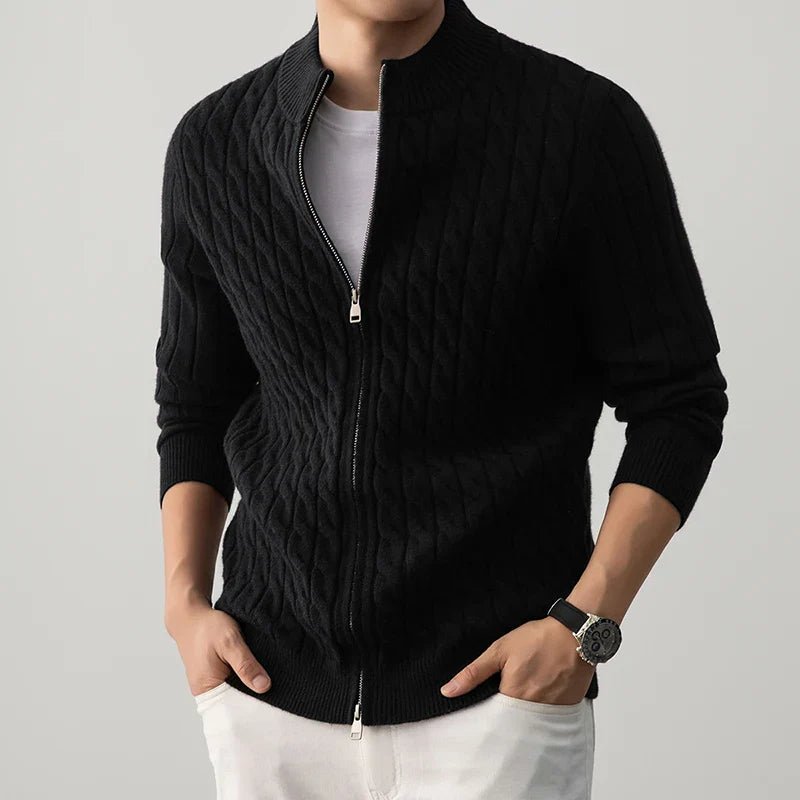 Person wearing a black zip-up sweater over a white shirt on a gray background