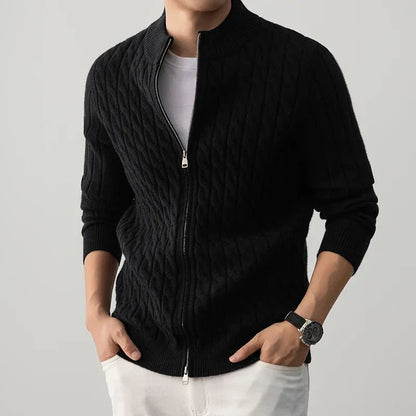 Person wearing a black zip-up sweater over a white shirt on a gray background