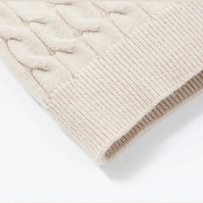 Close-up of a beige knitted sweater with cable pattern on a white background