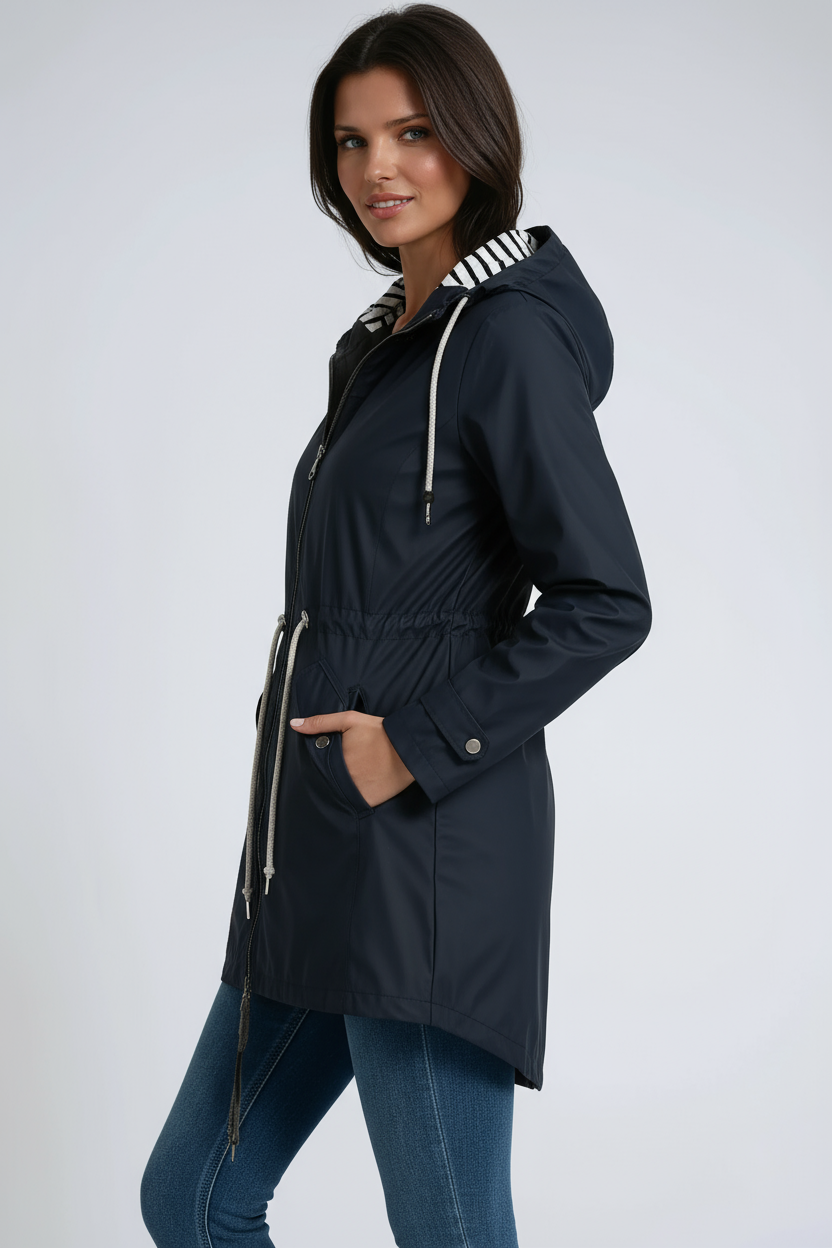 Woman wearing a navy blue raincoat with white accents on a light gray background