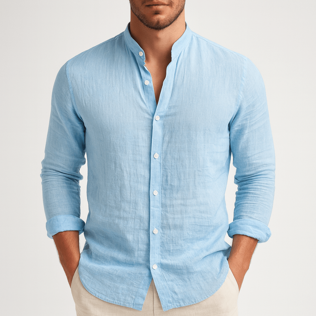 Man wearing a light blue button-up shirt with rolled-up sleeves on a plain background