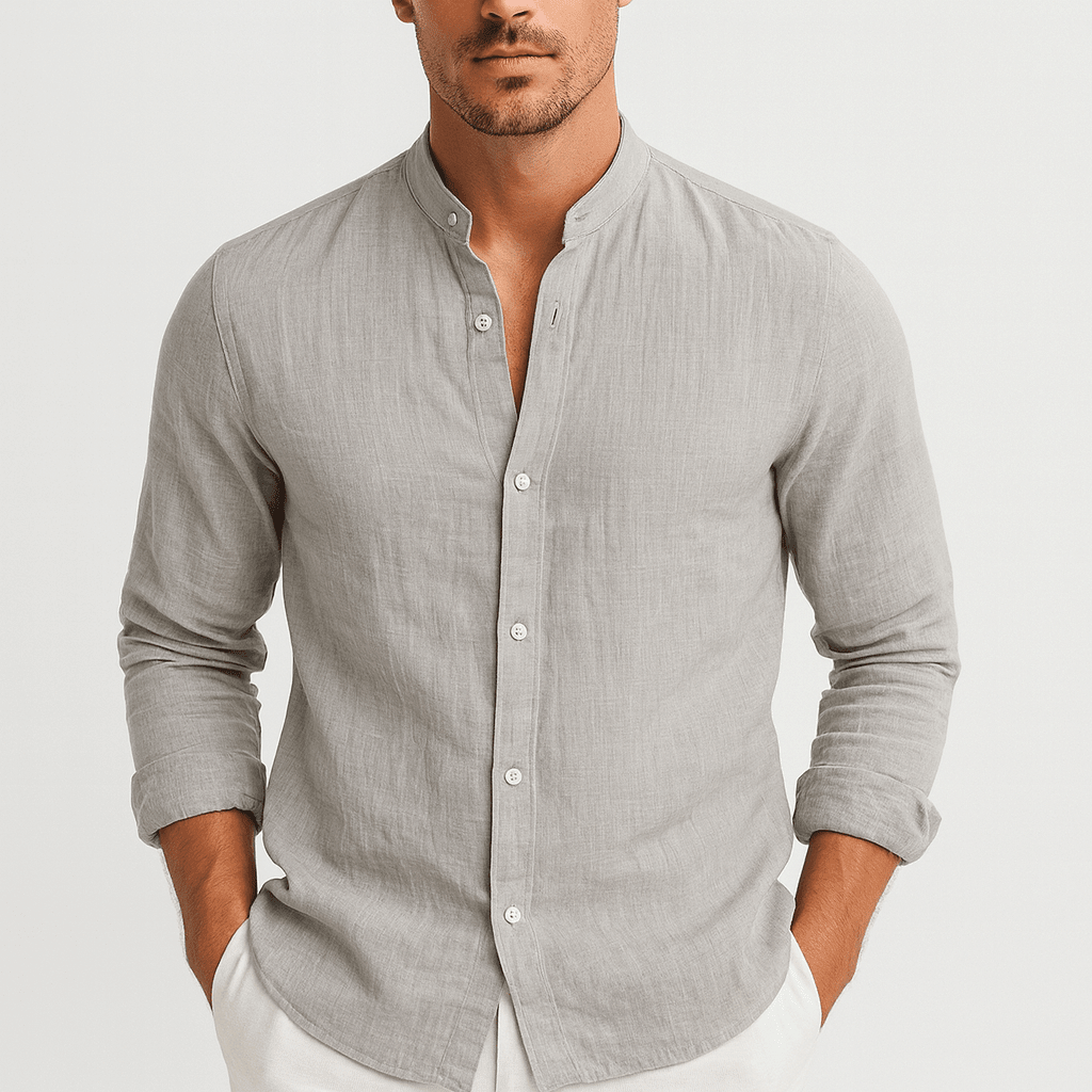 Man wearing a light gray button-up shirt with rolled-up sleeves on a plain background