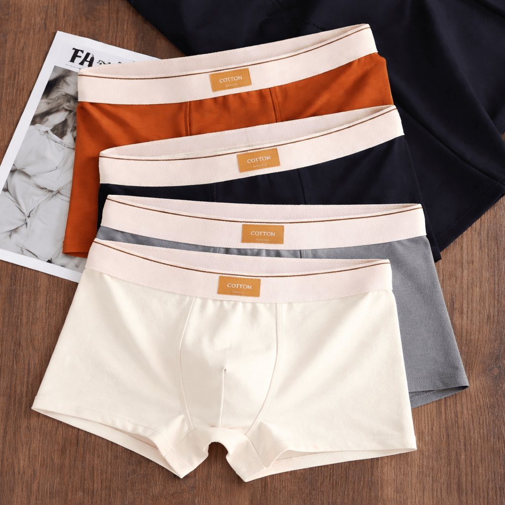 Four pairs of men's underwear in different colors on a wooden surface with a magazine underneath.