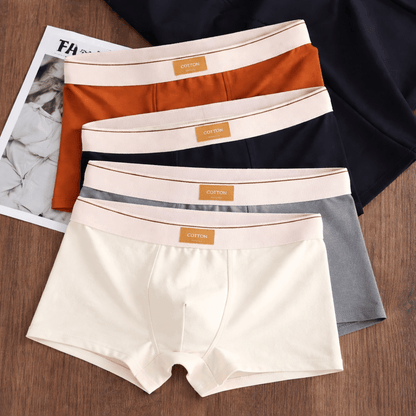 Four pairs of men's underwear in different colors on a wooden surface with a magazine underneath.