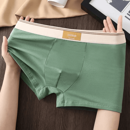 Green underwear held by hands on a wooden surface