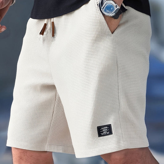 Close-up of a person wearing white checkered shorts with a blurred background
