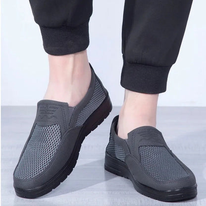 Gray slip-on shoes worn with black pants on a light gray background