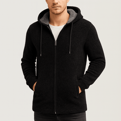 Man wearing a black zip-up hoodie on a light gray background