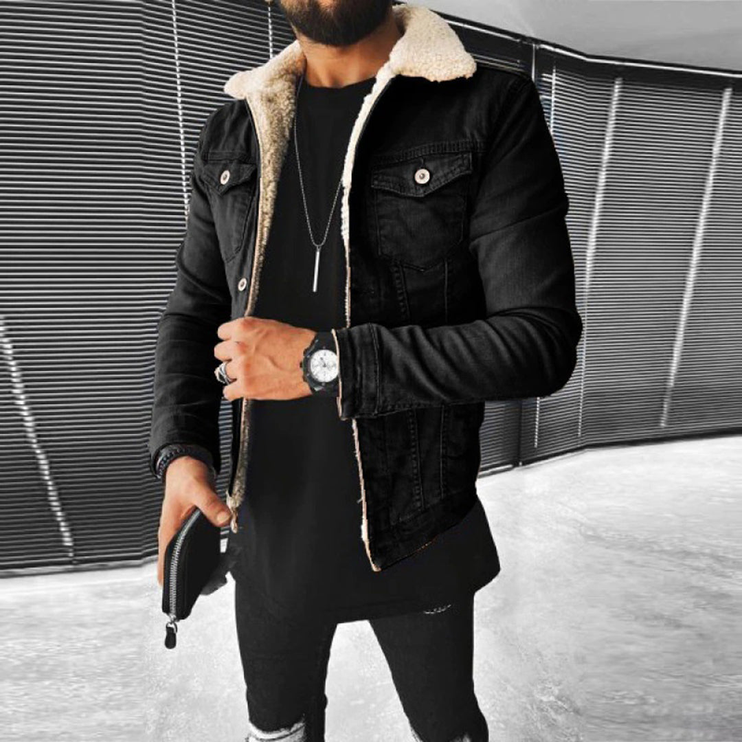 Person wearing a black denim jacket with shearling lining in an urban setting.
