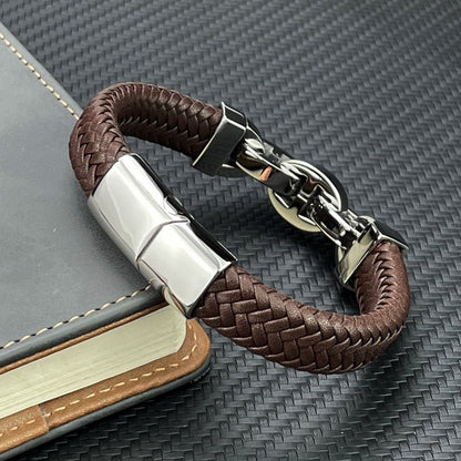 Brown braided leather bracelet with silver clasp on a textured surface