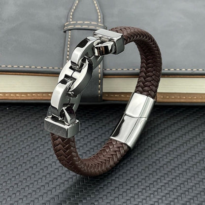 Brown braided leather bracelet with silver clasp on a textured surface