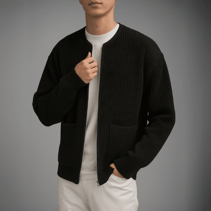 Person wearing a black ribbed sweater over a white shirt and pants on a gray background