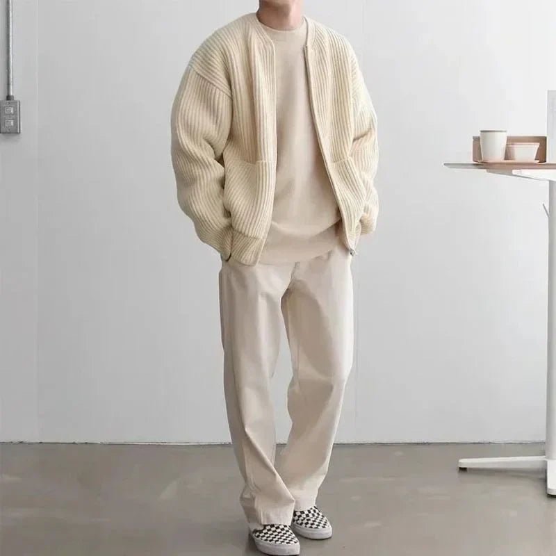 Person wearing a beige sweater and pants in a minimalistic room.