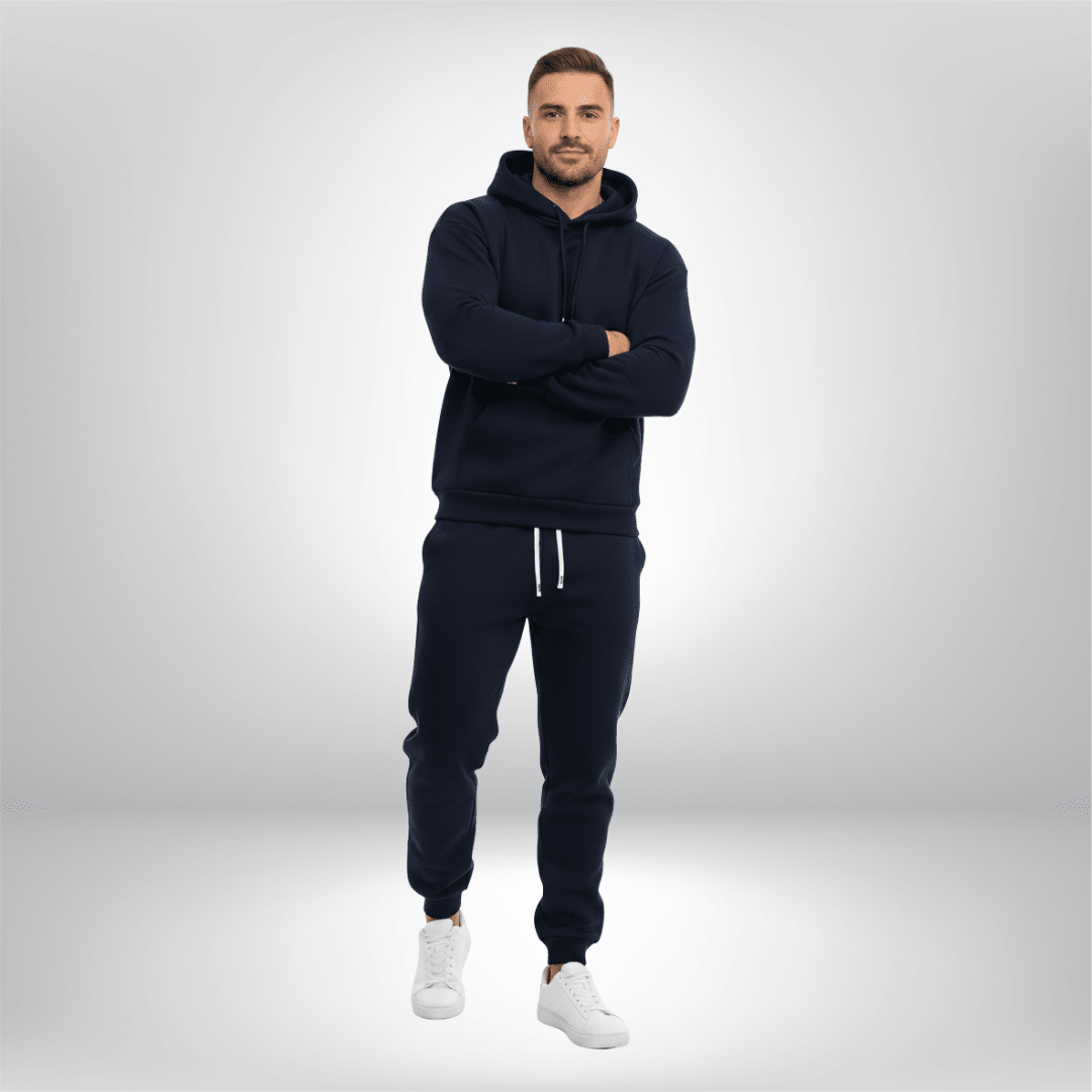 Man wearing a navy tracksuit with white shoes on a light gray background