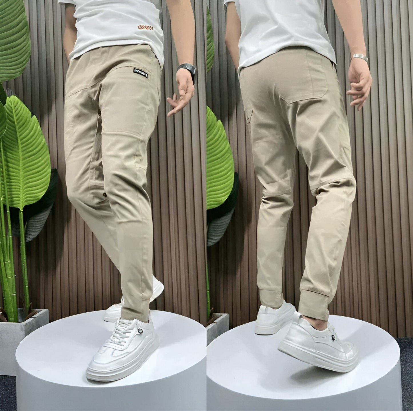 Two mannequins wearing beige pants and white sneakers in front of a striped wall.