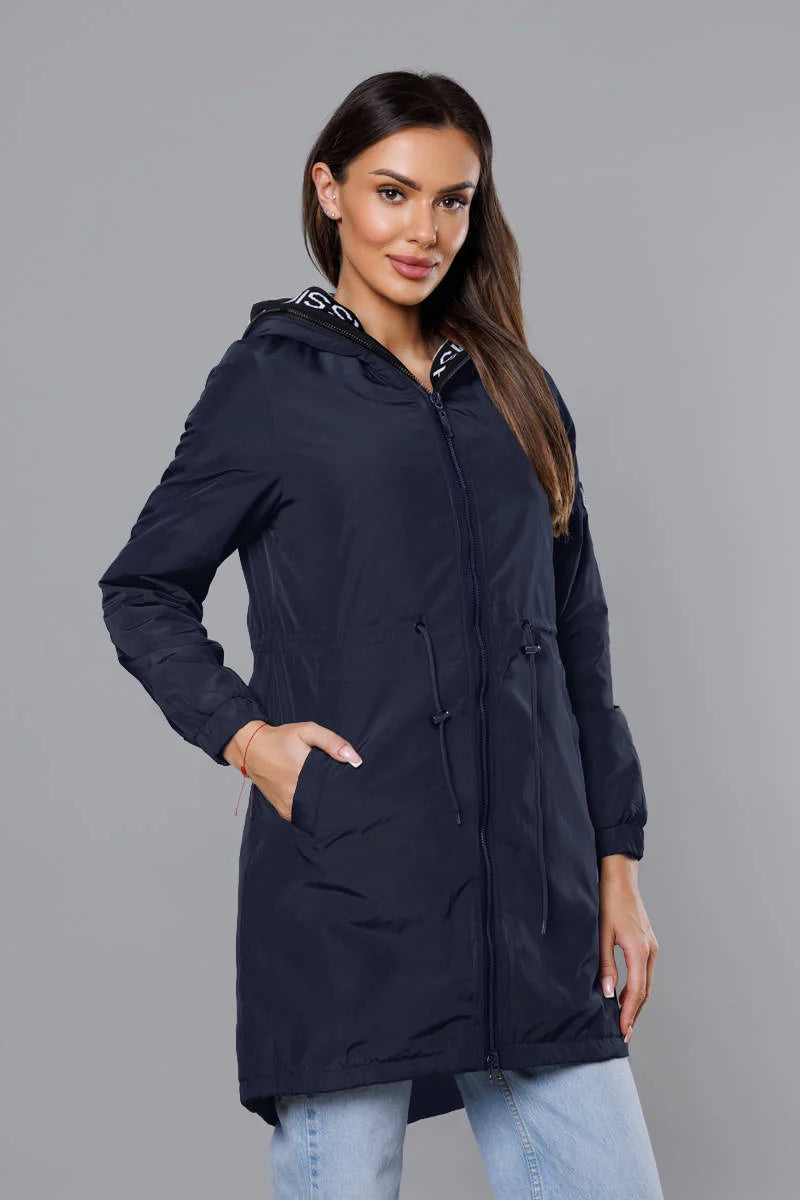 Woman wearing a navy blue hooded jacket against a gray background