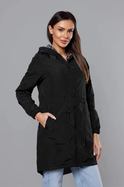 Woman wearing a black hooded jacket on a gray background