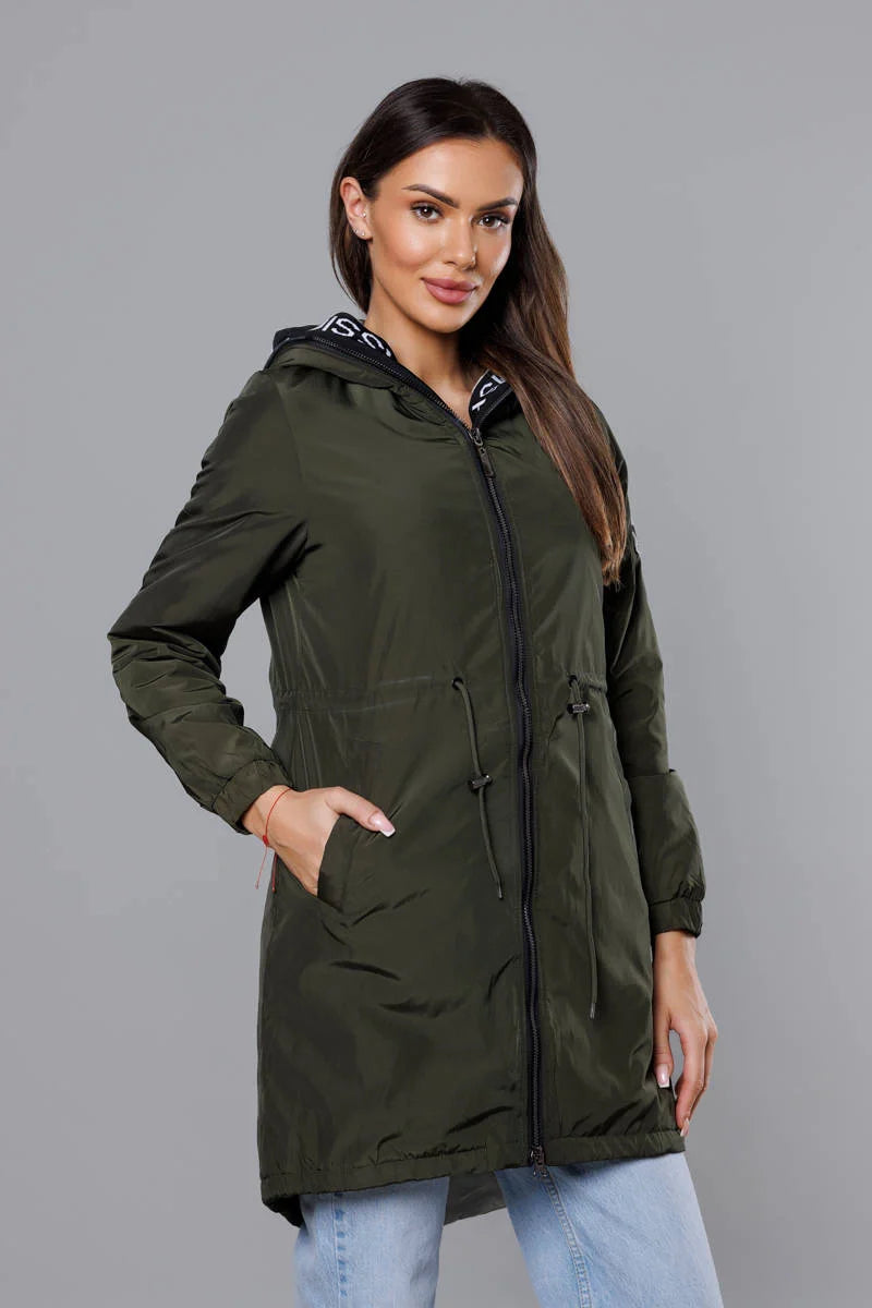 Woman wearing a green parka jacket against a gray background
