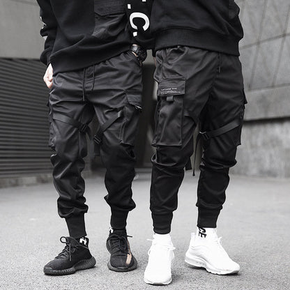 Two people wearing black cargo jogger pants and sneakers on a street.