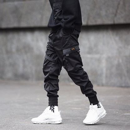 Person wearing black cargo pants and white sneakers on a gray pavement.