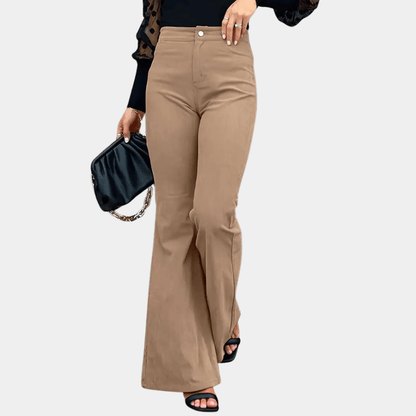 Person wearing beige pants holding a black clutch against a white background