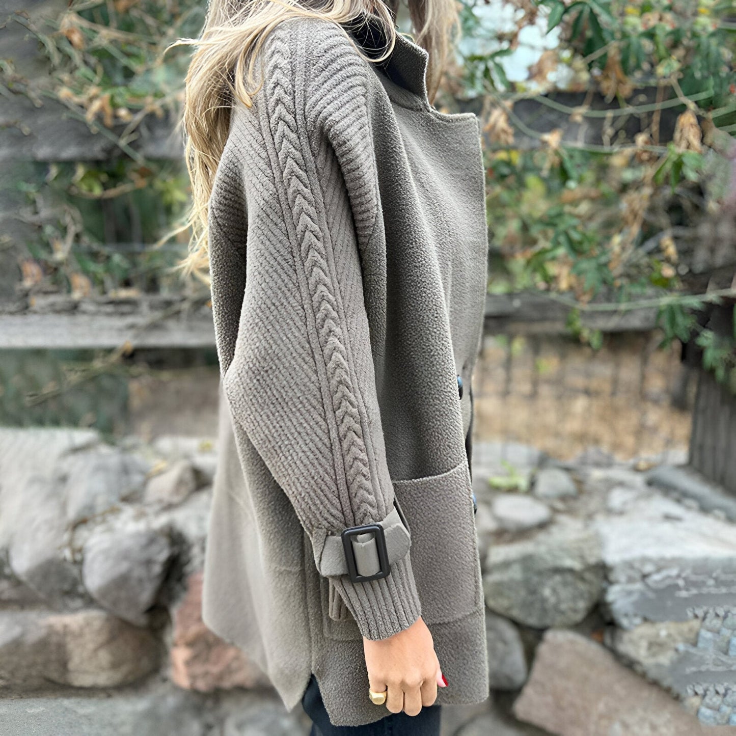 Person wearing a gray cardigan with a blurred background