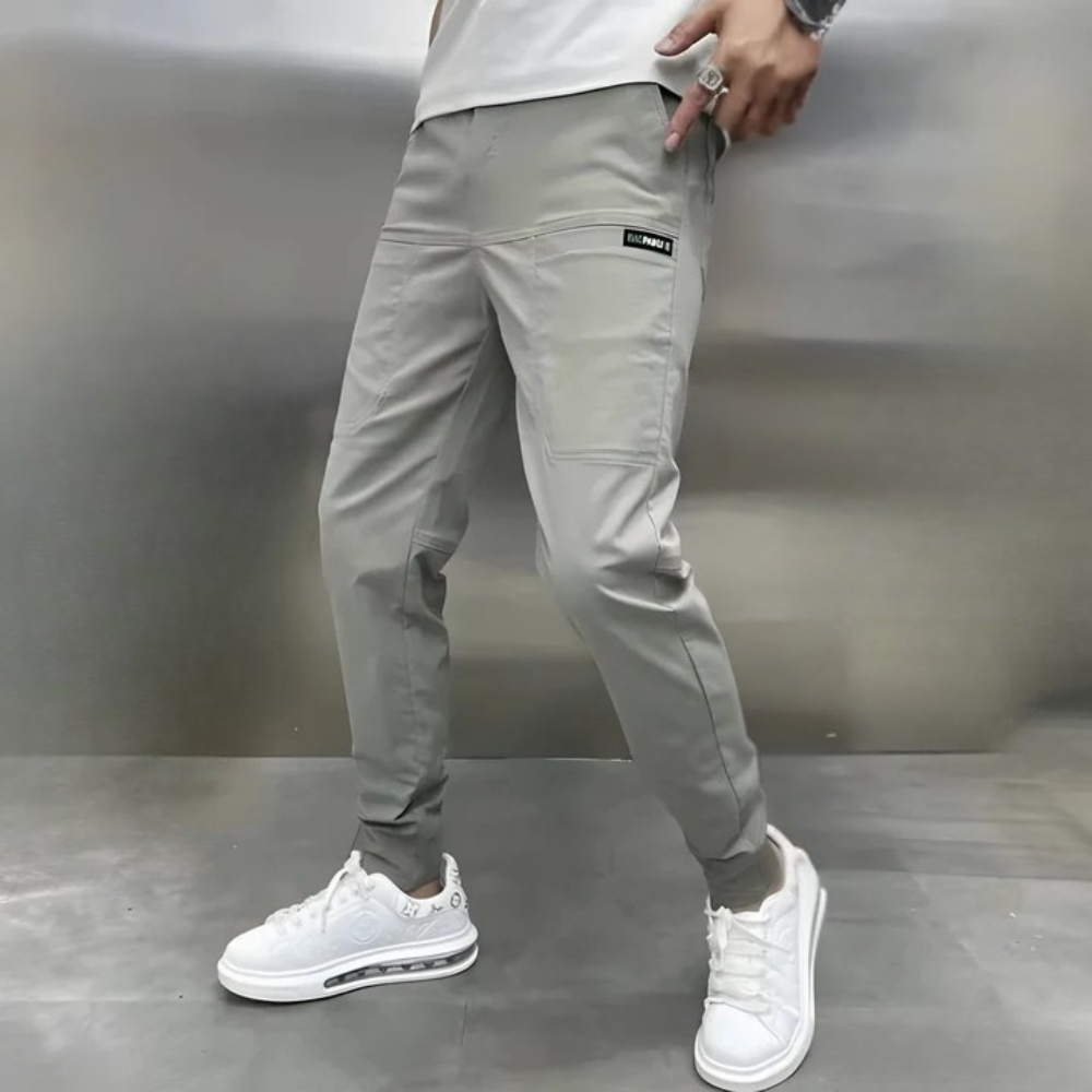 Person wearing gray jogger pants and white sneakers against a neutral background