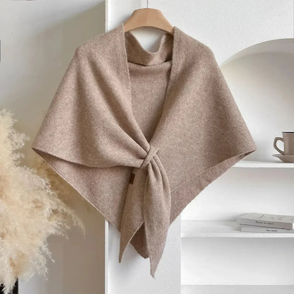 Beige shawl on a wooden hanger against a white wall with decor elements.