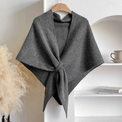 Gray poncho on a hanger against a neutral background