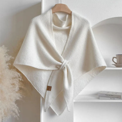 White poncho on a wooden hanger against a white background