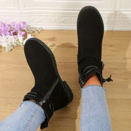 Person wearing black high-top sneakers on a wooden floor with light blue jeans.