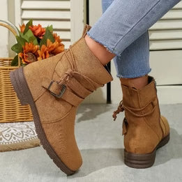 Brown ankle boots worn with light blue jeans on a neutral background