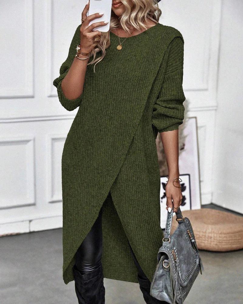 Woman wearing a green sweater holding a gray handbag indoors.