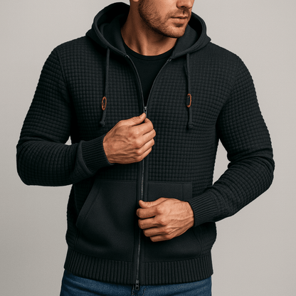 Man wearing a black textured hoodie against a plain background