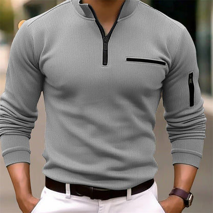 Gray ribbed sweater with black zipper and pocket details on a blurred background