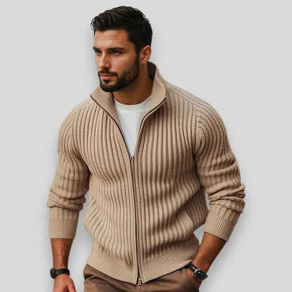 Man wearing a beige zip-up sweater against a plain background